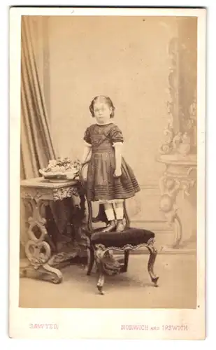 Fotografie Sawyer, Norwich, 46. London Street, Kleines Mädel im verzierten Rüschenkleid auf einem Stuhl stehend