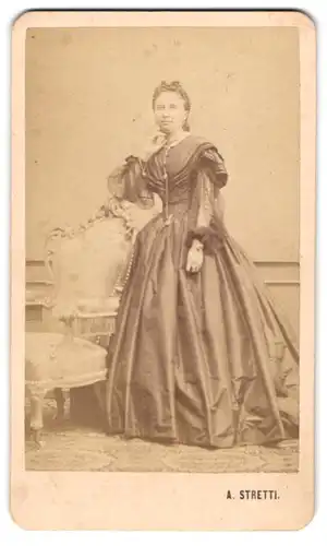Fotografie A. Stretti, Ort unbekannt, Portrait junge Dame im Biedermeierkleid mit Tüllärmeln und Kopfbedeckung