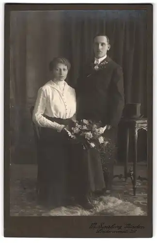 Fotografie M. Sensburg, München, junges Brautpaar im schwarzen Rock mit weisser Bluse und Brautstrauss