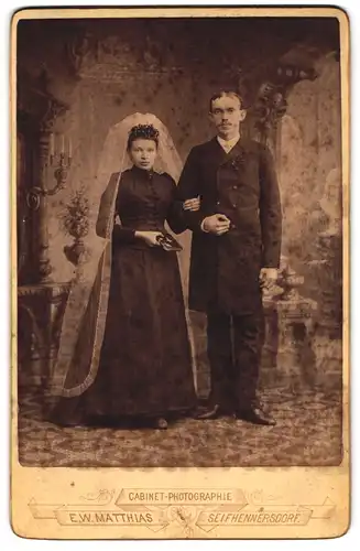 Fotografie E. W. Matthais, Seifhennersdorf, Portrait sächsisches Brautpaar im schwarzen Kleid und Anzug