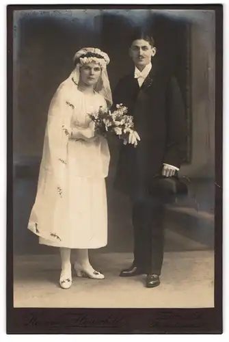 Fotografie Hermann Hauschild, Zittau i. Sa., Portrait junges Brautpaar am Hochzeitstag im Kleid und Anzug mit Zylinder