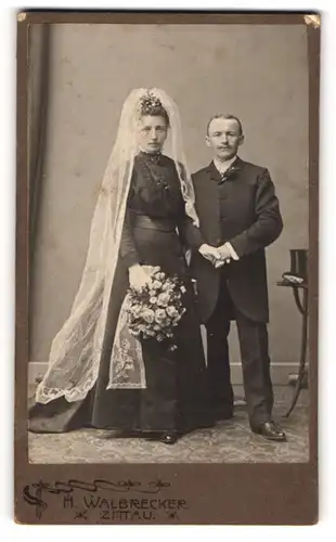 Fotografie H. WAlbrecker, Zittau i. Sa., Brautpaar mit schwarzen Kleid und kleinerer Mann im Anzug