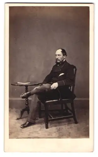 Fotografie The Bustins, Hereford, Gutbürgerlicher Herr im Anzug mit verschrenkten Beinen auf einem Stuhl sitzend