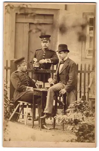 Fotografie unbekannter Fotograf und Ort, Portrait zwei Uffz. in Uniform beim Umtrunk mit Schwarzbier im Garten