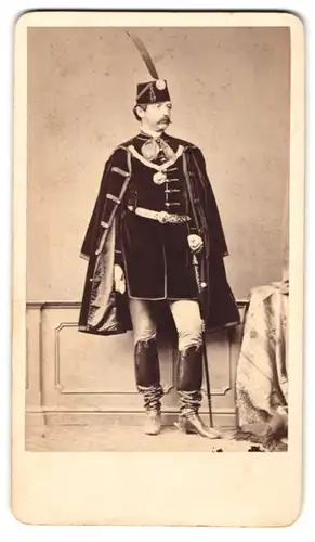 Fotografie Borsos es Doctor, Pesten, Portrait ungarischer Soldat in Uniform der Kavallerie mit Federhut und Säbel, Orden