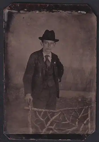 Fotografie Ferrotypie junger Mann im dunklen Anzug mit Hut posiert im Atelier
