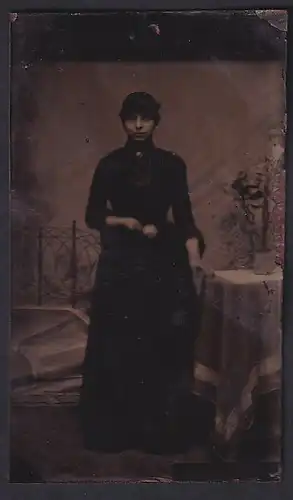 Fotografie Ferrotypie junge Dame im dunklen Kleid stehend am Tisch