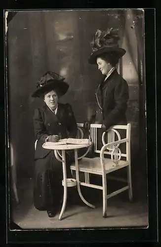 AK Frauen in schwarzen Kostümen auf einer Bank, beide mit Hut