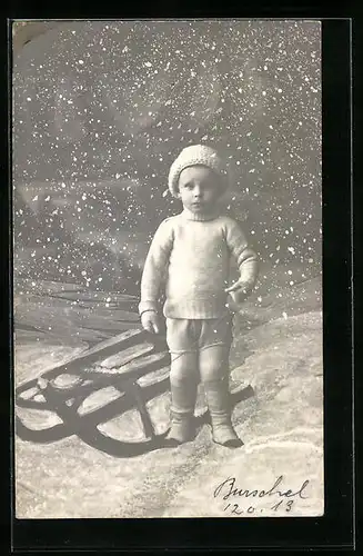 AK Kind neben ihrem Schlitten im Schnee