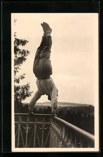 AK Mann macht Handstand auf dem Balkongeländer, Blick auf den Wald, turnen