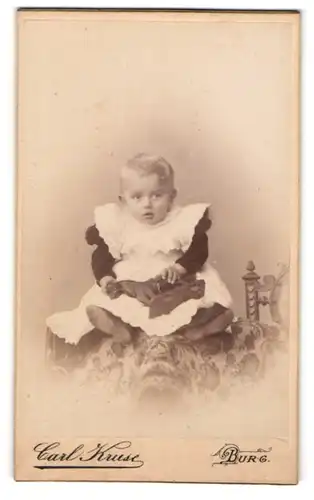 Fotografie Carl Kruse, Burg, Schartauer-Str. 16, Kleines Kind im Kleid mit Spielzeugpferd