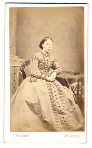 Fotografie F. Spalding, Chelmsford, Tindal Square, Junge Frau mit Duttfrisur in gemustertem Kleid mit weitem Rock
