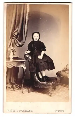 Fotografie Maull & Polyblank, London, 55. Gracechurch Street, Kleines Mädel im schwarzen Kleid auf einem Sessel stehend