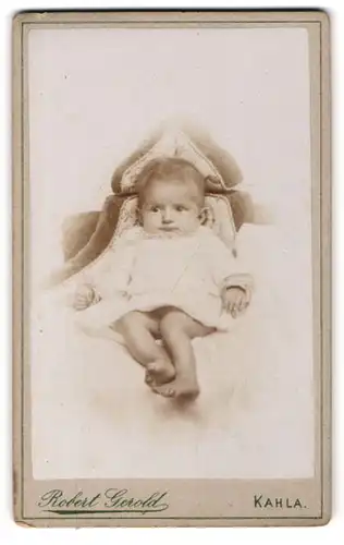 Fotografie Robert Geroldt, Kahla, Baby im Taufkleid auf einem Sitzmöbel