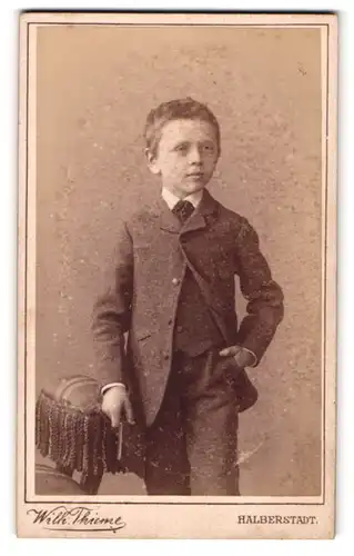 Fotografie Wilh. Thieme, Halberstadt, Plantage, Junge im Anzug mit Hand in der Tasche und Buch