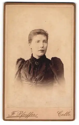 Fotografie F. Pfeiffer, Celle, Westcellerthorstrasse 15, Junge Frau mit Brosche in dunklem Kleid mit Puffärmeln
