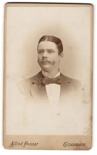 Fotografie Alfred Penner, Gumbinnen, Freundlicher junger Mann mit Mittelscheitel, Schnurrbart und Fliege