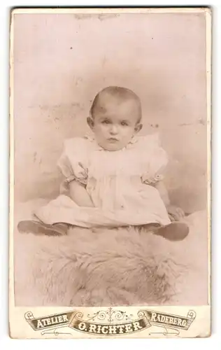Fotografie Otto Richter, Radeberg, Pulsnitzer-Str. 7, Süsses Kleinkind im Kleid sitzt auf Fell