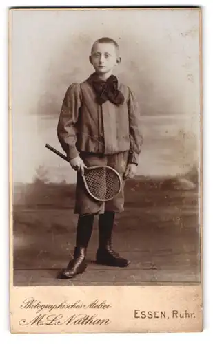 Fotografie M. L. Nathan, Essen /Ruhr, Junger Bursche mit Schleife am Kragen seines Hemdes und Tennisschläger in der Hand