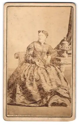 Fotografie W. H. Brunton & Co., Whitehaven, Wellington Row, Portrait Lady im Biedermeierkleid auf Sessel sitzend