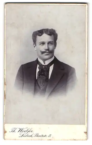 Fotografie Th. Woelfer, Lübeck, Breitestrasse 13, Junger Mann mit Moustache im modischen Gewand mit breitem Schlips