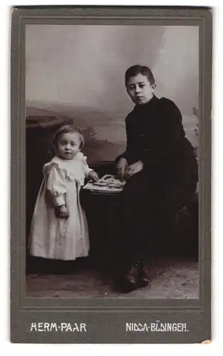 Fotografie Herm. Paar, Nidda, Halbwüchsiger Knabe in dunkler Kleidung mit kleinem Mädchen