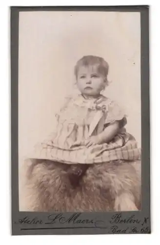 Fotografie L. Maerz, Berlin-N., Bad-Str. 65, Süsses Kleinkind im Kleid sitzt auf Fell