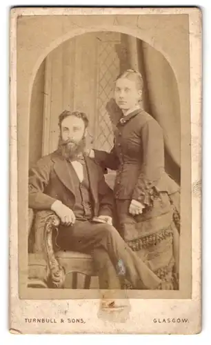 Fotografie Turnbull & Sons., Glasgow, 75. Jamaica Street, Sitzender Mann mit Frau im geschmückten Kleid