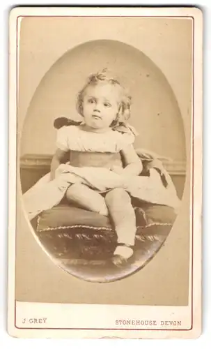 Fotografie J. Grey, Stonehouse Devon, 60, Union St., Kleine Mädchen im Kleid sitzt auf Kissen