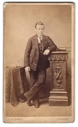 Fotografie James Bowman, Glasgow, 65 Jamaica Street, junger Herr im Anzug an Möbel lehnend