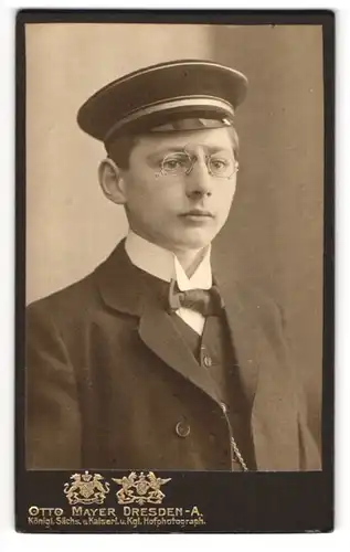 Fotografie Otto Mayer, Dresden, Portrait junger Student im Anzug mit Fliege und Schirmmütze, Zwickerbrille