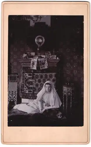 Fotografie unbekannter Fotograf und Ort, junge Frau liegt auf einem Bärenfell mit Kopftuch, Interior