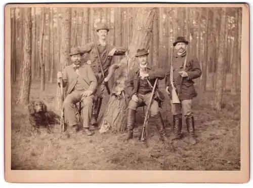 Fotografie unbekannter Fotograf und Ort, vier Jäger mit ihren Flinten und Jagdhund posiern im Wald, Toter Fuchs am Baum
