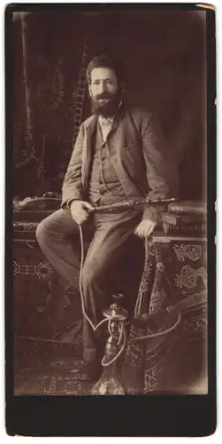 Fotografie unbekannter Fotograf und Ort, Portrait Mann im Anzug mit Wasserpfeife und Vollbart posiert im Atelier