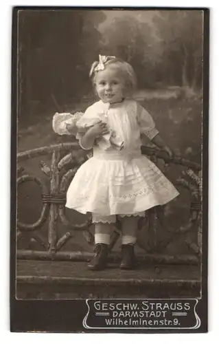 Fotografie Geschwister Strauss, Darmstadt, Wilhelminenstrasse 9, Kleines Mädchen mit Haarschleife und Puppe