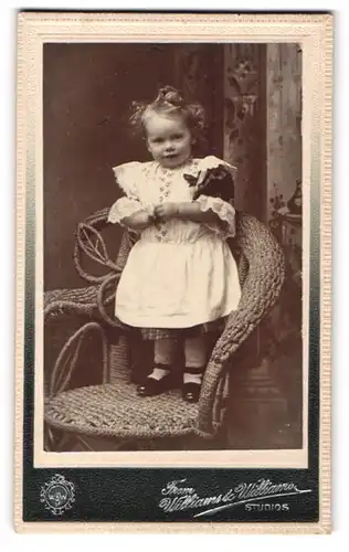 Fotografie Williams & Williams, Ort unbekannt, Kleines Mädchen im hübschen Kleid