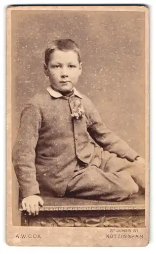 Fotografie A. W. Cox, Nottingham, 11. St. James Street, Junge im Anzug auf Tisch sitzend