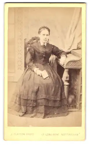 Fotografie J. Clayson, Nottingham, 17. Long Row, Dame im Kleid auf Stuhl sitzend mit Buch in der Hand