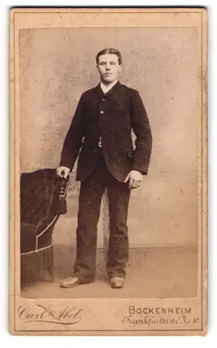 Fotografie Carl Abel, Bockenheim, Frankfurterstr. 16, Stehender junger Herr im Anzug an Sessel abstützend