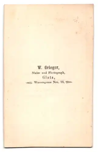 Fotografie W. Grieger, Glatz, Wassergasse 88, Portrait älterer Herr im Anzug mit weisser Hose posiert sitzend im Atelier