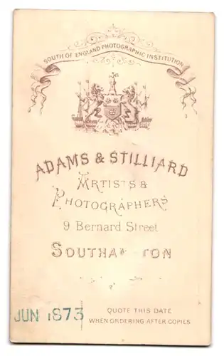 Fotografie Adams & Stilliard, Southampton, hübsche junge Engländerin im Biedermeierkleid stehend am Sekretär