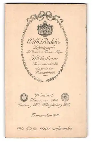 Fotografie Wilhelm Redeke, Hildesheim, Kreuzstr. 22, Wappen im Kranz, Rückseitig Baby auf Bank liegend