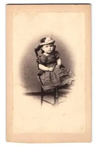 Fotografie unbekannter Fotograf und Ort, genervt schauendes Mädchen im Kleid mit Hut