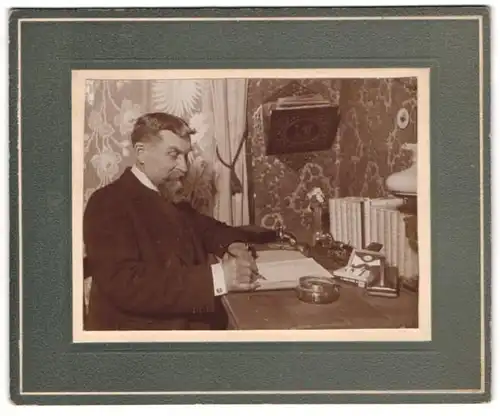 Fotografie unbekannter Fotograf und Ort, älterer Herr schreibt einen Brief an seinem Schreibtisch, Zigarettenetui, 1924