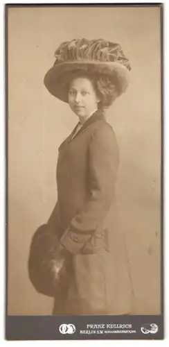 Fotografie Franz Kullrich, Berlin, Portrait junge Frau im dunklen Mantel mit Muff und grossen Hut