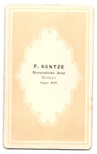 Fotografie F. Kuntze, Erfurt, Anger 1698, Portrait junger Mann im Anzug mit Mantel und Hut auf dem Tisch