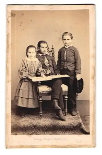Fotografie Berger & Meckes, Ulm, Portrait Kinder in Anzügen und im Biedermeierkleid blätter in einem Fotoalbum
