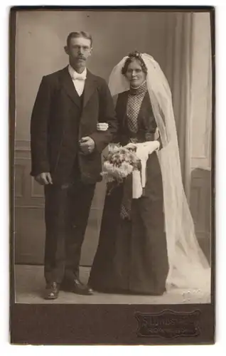 Fotografie S. Lundström, Ronneby, junge Brautleute im schwarzen Hochzeitskleid und Anzug, Brautstrauss