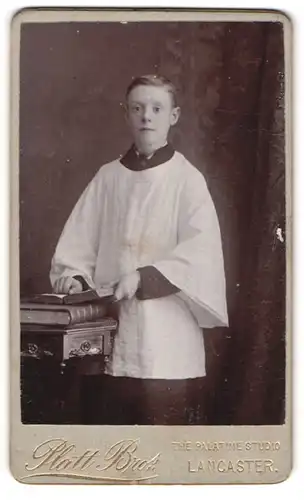 Fotografie Platt Bros., Lancaster, junger Knabe als Messdiener im Gewand mit aufgeschlagener Bibel