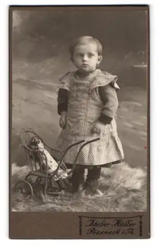 Fotografie Atelier Müller, Pössneck i. Th., kleines Mädchen im karierten Kleid mit Puppenwagen und Puppe